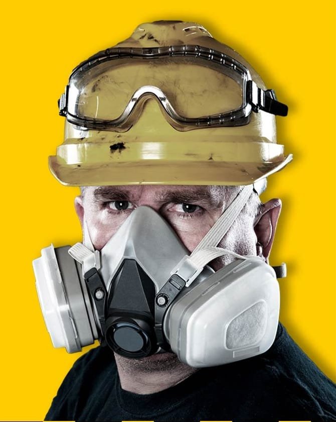 Safety professional wearing a hard hat, goggles and half-face respirator